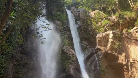 Twin Mok Fa Waterfall cascading down steep rocky cliff with tropical forest Video stock 330985004