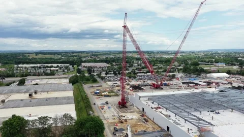 Twin red cranes tower above data center under construction, with steel frame Stock Footage 337529339