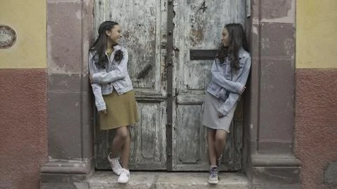 Twin Sisters in Denim Jackets Hanging Out in Front Of Worn Down Door Stock Photos