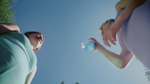 Twin sisters drinking water from a bottle after a fitness workout Видео 336960629