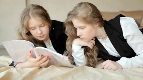 Twin sisters leaf through the book Video stock 63122933