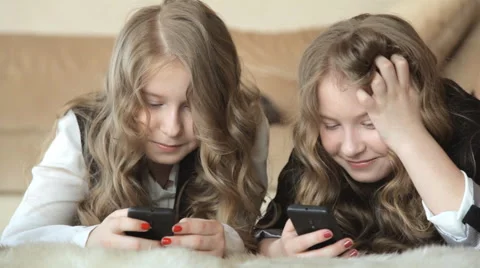 Twin sisters write messages in the phone and laughing Stock Footage 63122886