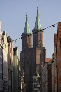 Twin-spired brick cathedral framed by narrow townhouses Stock Photos