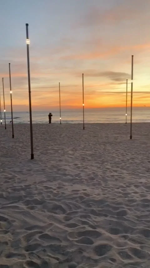 Twinkling light posts on tropical beach at sunset Stock Footage 136340365