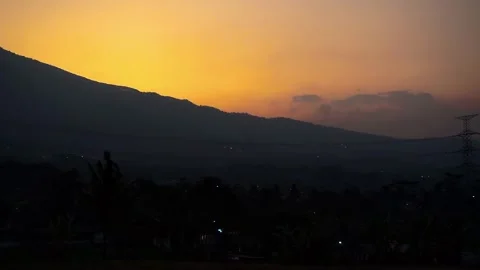 Twinkling night lights against a backdrop of mountains and sunset Stock Footage 252058671