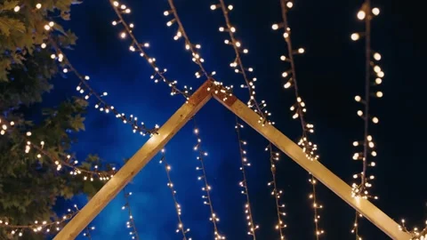 Twinkling string lights over wooden arch under deep blue night sky with festive Stock Footage 313653372