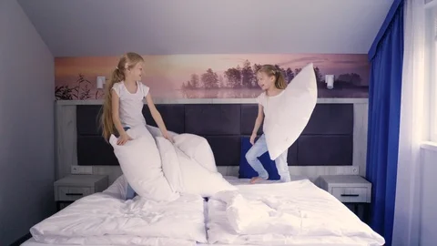 Twins fighting with pillows on bed 스톡 동영상 107407609
