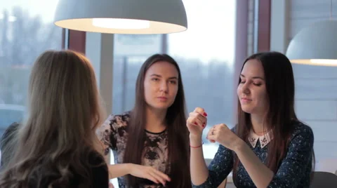 Twins talking with a friend while looking at each other in cafe 스톡 동영상 60716083