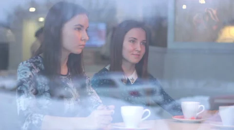 Twins talking with a friend while looking at each other in cafe Vidéo 60746334