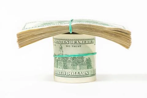 A twisted bundle of 100 dollar bills stands on packs of dollars. Stock Photos