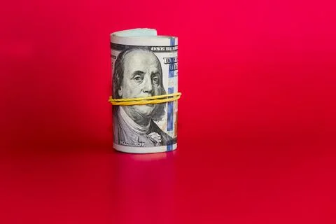 Twisted bundle 100 dollar bills on a red background, blood money, money earne Stock Photos