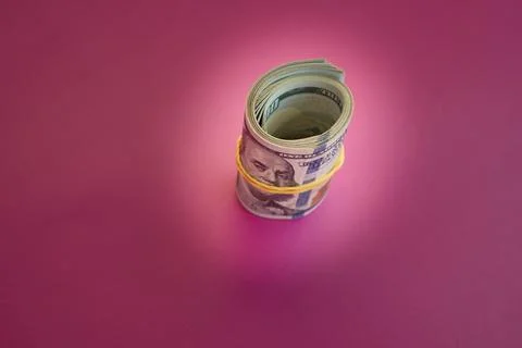 Twisted bundle 100 dollar billson pink background, hundred dollar notes on pi Stock Photos