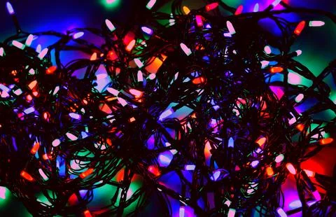 Twisted festive garland with multi colored lights glowing in the dark Stock Photos