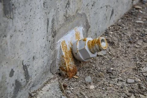 Twisted metal nut covered with rust on the concrete wall of the bridge Stock Photos