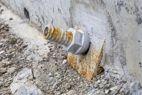 Twisted metal nut covered with rust on the concrete wall of the bridge Stock Photos
