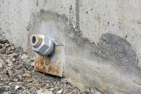 Twisted metal nut covered with rust on the concrete wall of the bridge Stock Photos