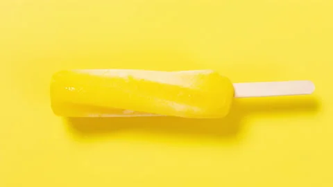 Twisted shaped pineapple flavor popsicle melting timelapse on yellow at top a Stock Footage 201394234
