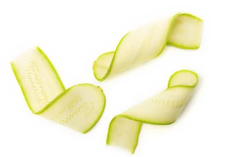 Twisted thin slices of green squash on white background Stock Photos