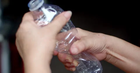 Twisting an empty plastic bottle by hand to compact its size for efficient. Stock Footage 311596491