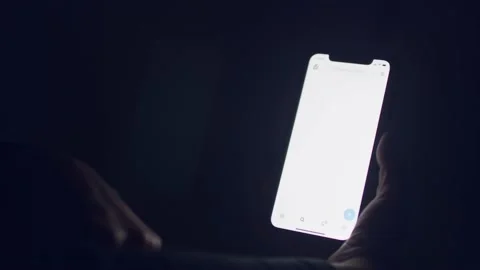 Twitter - In the darkness a smartphone screen glows as a person opens and Stock Footage 220948954