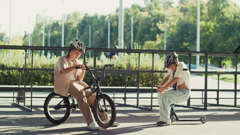 Two 10 Year Old Boys Distracted by Smartphones with BMX and Scooter Video stock 346171601