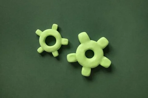 Two 3d gears of different sizes on a green background. Mechanism elements Foto stock