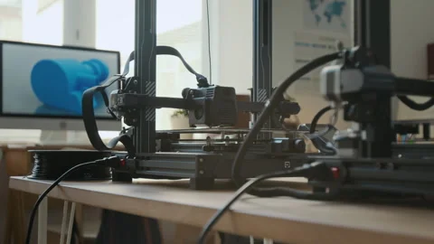 Two 3D Printers on Wooden Table Alongside Computer Displaying 3D Model in School Stock Footage 301921147
