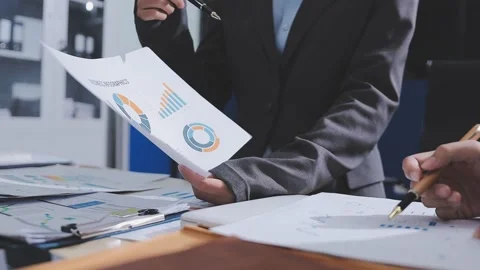 Two accountants examining financial documents using a calculator, taking no.. Stock Footage 336017486
