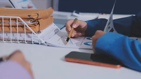 Two accountants examining financial documents using a calculator, taking no.. Stock Footage 336019230