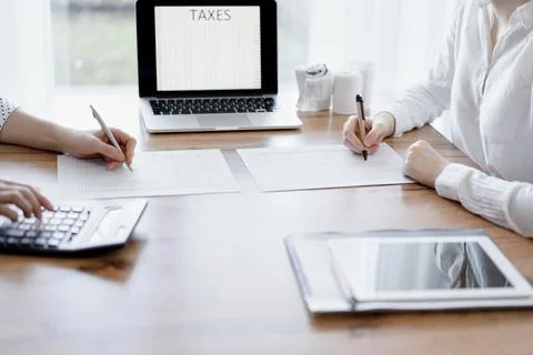 Two accountants using a laptop computer and calculator while counting taxes at Stockfoto's
