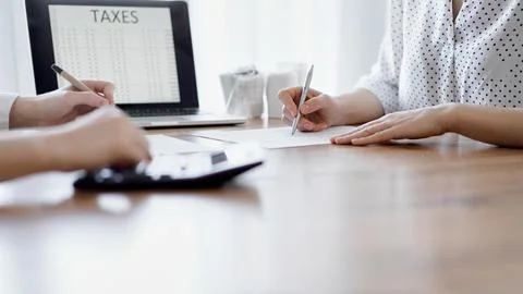 Two accountants using a laptop computer and calculator while counting taxes at Stock Photos