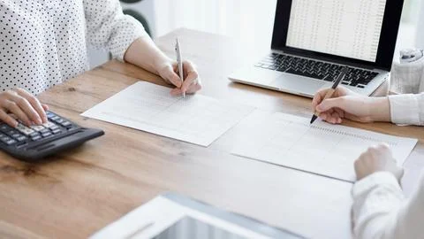 Two accountants using a laptop computer and calculator while counting taxes at Stockfoto's