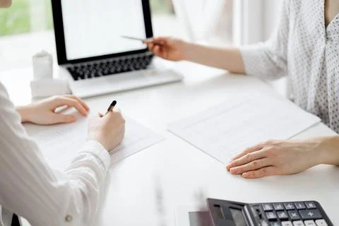 Two accountants using a laptop computer for counting taxes at white desk in Stockfoto's