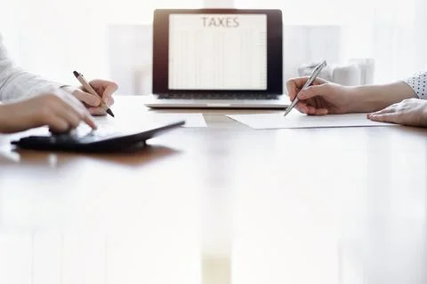 Two accountants using a laptop computer and calculator while counting taxes at Stock Photos