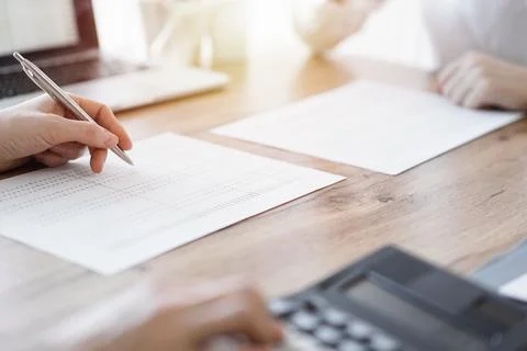 Two accountants using a laptop computer and calculator while counting taxes at Photos