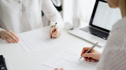Two accountants using a laptop computer for counting taxes at white desk in 库存照片