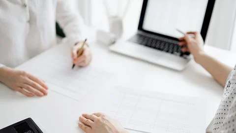 Two accountants using a laptop computer for counting taxes at white desk in Stock Photos