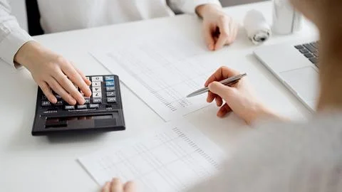 Two accountants using a laptop computer and calculator for counting taxes at Stock Photos