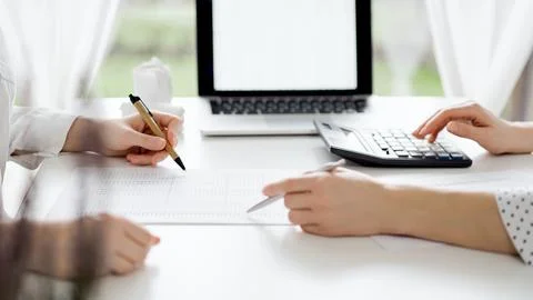 Two accountants using a laptop computer and calculator for counting taxes at Stockfoto's