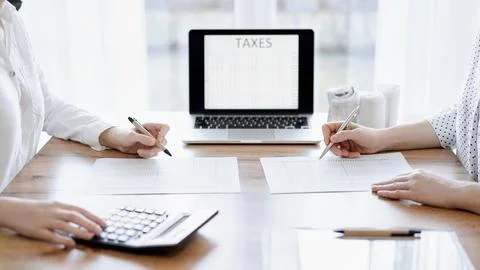 Two accountants using a laptop computer and calculator while counting taxes at Stockfoto's