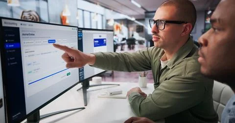 Two Accountants Work Together On Computer Analyzing Bank Transactions For Bus 스톡 사진