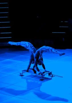Two acrobats perform a doubles stunt. uv costume Stock Photos
