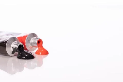 Two acrylic paint tubes red and black colours reflected in glass table surface Stock Photos