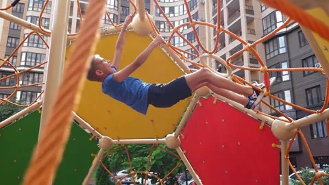 Two active boys climb a rope slide on the playground in the courtyard. Stock Footage 287585901