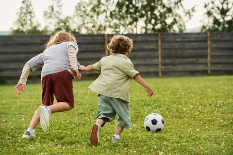 Two Active Children Playing Soccer on Green Lawn Outdoors Stock-Fotos