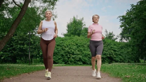 Two Active Senior Women Jogging Together in Green Park Stock Footage 341695122