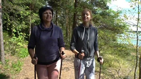 Two active women do Nordic walking in Park. Tracking shot. Slow motion Stock Footage