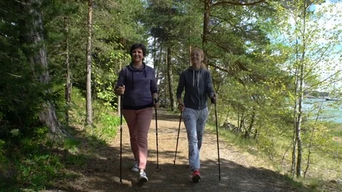 Two active women do Nordic walking in Park. Tracking shot. Slow motion Stock Footage 76183523