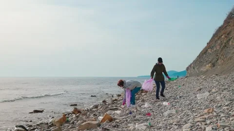Two activists remove garbage from a wild coastline to prevent pollution 库存影片 314892081