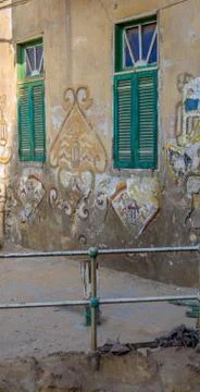 Two adjacent broken windows with closed green shutters and grunge stone wall Stock Photos